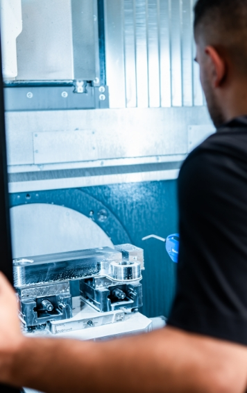 Ein Mann beobachtet eine moderne CNC-Maschine bei der Arbeit.