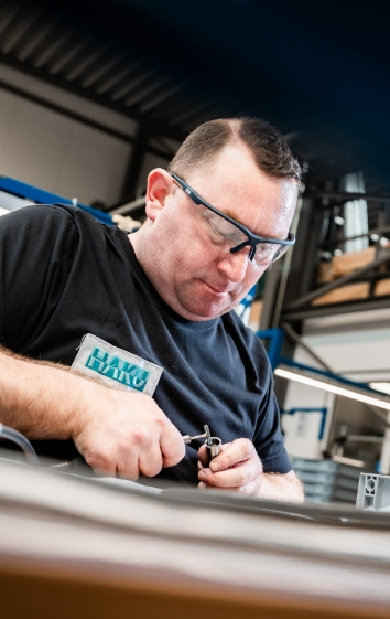 Ein Mann mit Schutzbrille arbeitet konzentriert an einem technischen Gerät in einer Werkstatt.