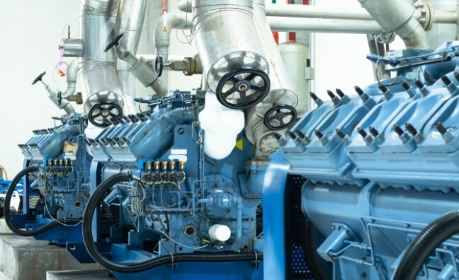 Eine Reihe von blauen Motoren mit Rohren und Ventilen in einer Industrieumgebung.