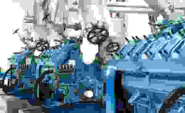 Eine Reihe von blauen Motoren mit Rohren und Ventilen in einer Industrieumgebung.